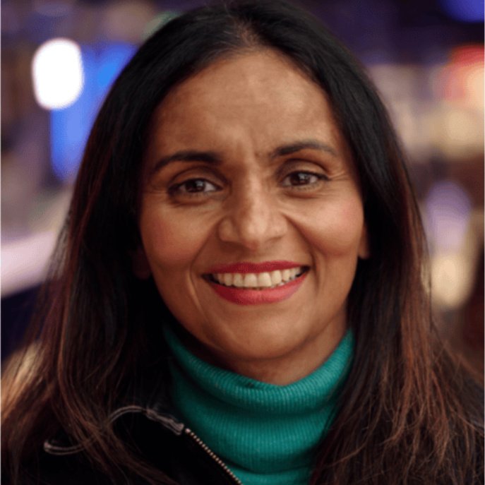 Head and shoulder AI genrated portrait of a smiling woman with brown long hair wearing a green rollneck jumper